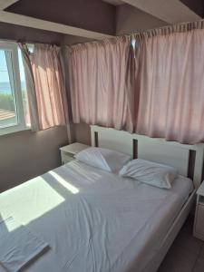 a bedroom with a bed with white sheets and a window at Villa Giotis in Skala Sotiros