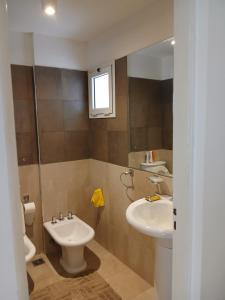 a bathroom with a sink and a toilet and a mirror at Punto Sur Apart in Río Cuarto