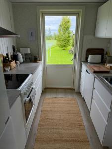 a kitchen with a door with a view of a yard at Litet hus på landet in Krokom +9 photos