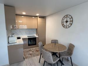 a kitchen with a table and chairs and a clock on the wall at Smiltelė apartamentai in Varėna