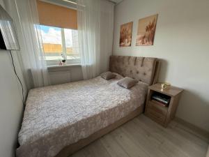 a small bedroom with a bed and a window at Smiltelė apartamentai in Varėna