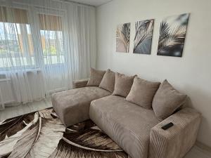 a living room with a couch and two paintings at Smiltelė apartamentai in Varėna