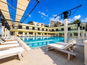a building with a swimming pool with benches in front of it at Shala Resort & SPA in Durrës