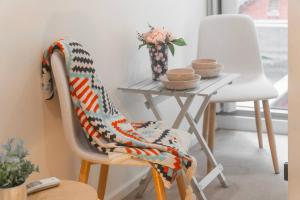 a chair with a blanket on it next to a table at Puddings Home Compact Apartment State Library in Melbourne
