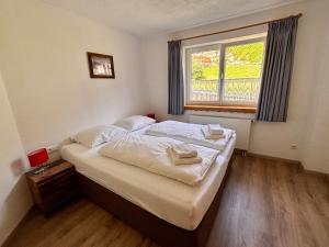 a bedroom with a bed with white sheets and a window at Landhaus Cornelia in Berwang