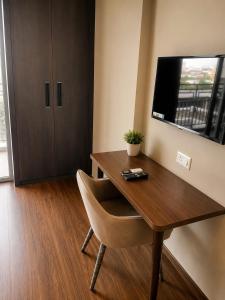 a wooden desk with a chair and a television on a wall at Velvet Nook in Greater Noida