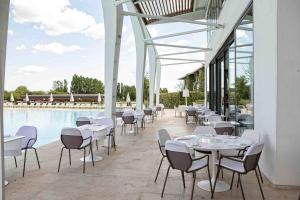 un restaurante con mesas blancas y sillas junto a una piscina en Riviera Golf Resort en San Giovanni in Marignano