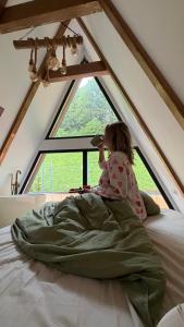 a little girl sitting on a bed in front of a window at Mia A-Frame Chalet Cheia in Cheia