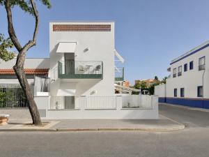 a white building with a tree in front of it at Villa Julia Apartamentos in Chipiona