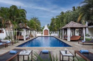 a pool at a resort with tables and chairs at La palm Luang prabang in Luang Prabang