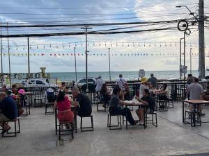 a group of people sitting at tables near the beach at New Abani in Jomtien Beach