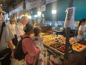 a group of people standing around a market with food at New Abani in Jomtien Beach