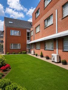 a brick building with a green lawn in front of it at Hotel Taormina Brussels Airport in Zaventem