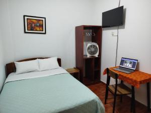 a bedroom with a bed and a laptop on a desk at BACHÍG Hospedaje in Moyobamba