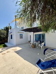 a patio with chairs and an umbrella and a building at Spacious villa for holidays in Kerkouene