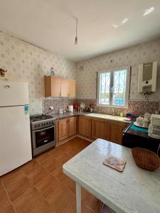 a kitchen with a white refrigerator and a table at Spacious villa for holidays in Kerkouene