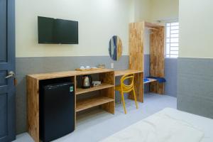 a room with a tv and a desk with a refrigerator at De Rivé Homestay - Bến Ninh Kiều in Can Tho