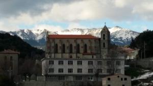 a building with a church and mountains in the background at A casa di catharina appartement in Zicavo