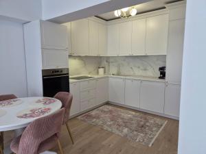 a kitchen with white cabinets and a table with chairs at Apartament Nagiulia in Oradea