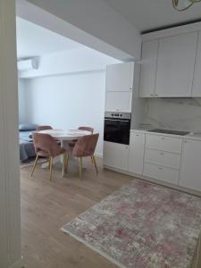 a kitchen with white cabinets and a table and chairs at Apartament Nagiulia in Oradea