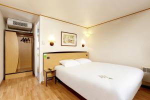 een slaapkamer met een groot wit bed in een kamer bij Campanile Alençon in Alençon