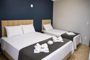 two beds in a room with white flowers on them at Pousada Recanto das Águas - Fama MG in Fama