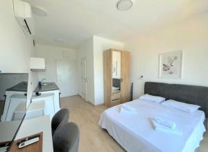 a bedroom with a white bed and a kitchen at Cosy Adriatic Studio in Kotor