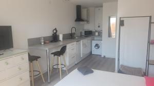 a kitchen with a counter and stools in it at Studio NEUF et élégant avec CLIM in Tarbes