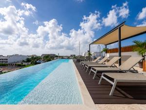 a pool on the roof of a building with lounge chairs at Papaya 15 Apartments in Playa del Carmen