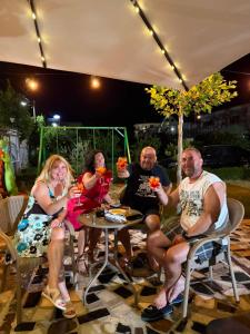 a group of people sitting at a table under an umbrella at Hotel Aleksi Velipojë in Velipojë