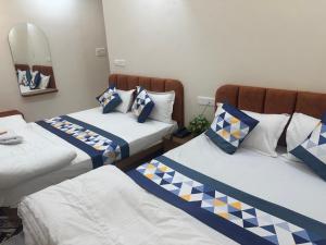 a room with two beds with blue and white pillows at Hotel G17 Dhamnod in Dhāmnod