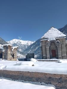 a building covered in snow with mountains in the background at Khan Camping Naranag in Sonāmarg