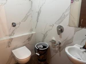 a white bathroom with a toilet and a sink at Hotel G17 Dhamnod in Dhāmnod
