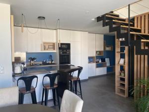 a kitchen with a counter and some bar stools at Lilau - Villa de charme avec parking et jardin près de Chantilly in Gouvieux