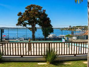 a wooden fence with a tree in front of the water at Pousada Recanto das Águas - Fama MG in Fama