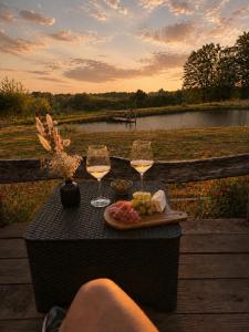 a table with two glasses of wine and a plate of food at Cocolac- gîte avec étang privé en Corrèze- in Lubersac