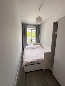 a small bedroom with a bed and a window at Apartament Modrzewia in Elblag