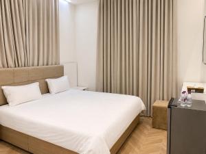 a bedroom with a large white bed and curtains at Bin Fhaid Suites in Salalah