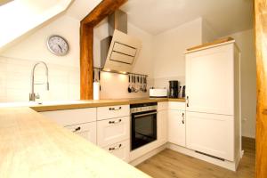 a kitchen with white cabinets and a clock on the wall at Kapitänsdeck in Wustrow