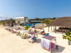 a row of tables and chairs on a beach at Canary Kendwa Beach Resort in Kendwa