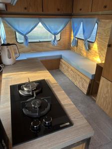 a kitchen with a stove in a tiny caravan at Pole namiotowe u Józia in Borne Sulinowo