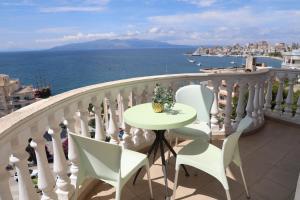 a table and chairs on a balcony with the ocean at Saranda Apartaments Meta in Sarandë