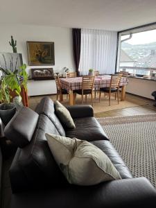 a living room with a black leather couch and a dining room at Stadtvilla Annabelle - mit Sauna in Meschede