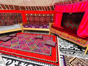 a room with two beds and red curtains and colorful rugs at Aspan Kazakh Ger Camp in Ölgiy