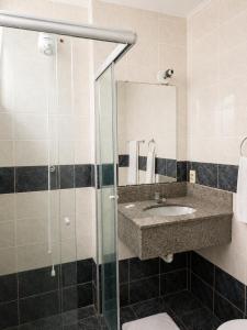 a bathroom with a sink and a glass shower at Palace Hotel in Itajubá