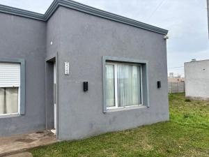 a gray house with two windows and a door at Alumine in Coronel Suárez