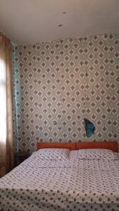 a bedroom with a bed with a blanket and a wall at Ushba Hearth House in Tvebishi
