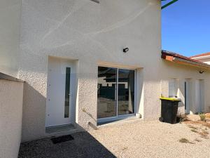 a white house with a door and a trash can at Duplex du Paradis 2 chambres in Saint-Romain-de-Jalionas