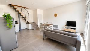 a living room with a couch and a television at Duplex du Paradis 2 chambres in Saint-Romain-de-Jalionas