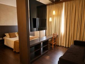 a hotel room with a bed and a desk with a television at Palace Hotel in Itajubá